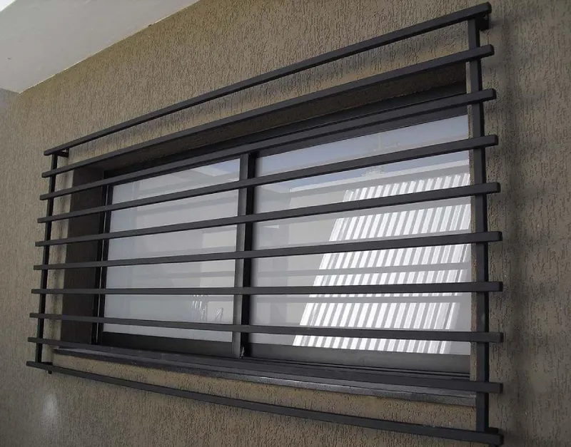A rectangular window with black metal security bars arranged horizontally, set in a textured beige wall, showcases the sturdy protection provided by Burnaby Aluminum Window Grates.